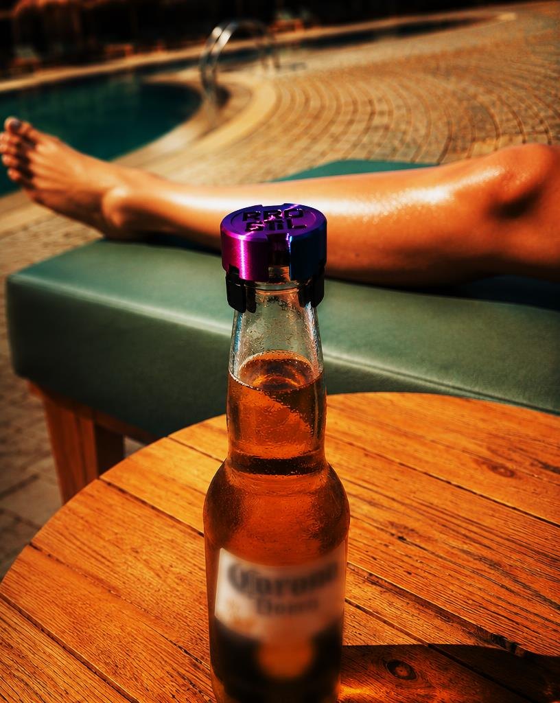 Flasche mit lila SafeCap auf einem Tisch am Pool